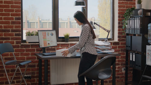 Side view of woman sitting on chair at home