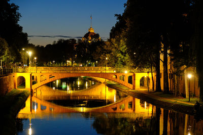 Bridge over river in city against sky at night