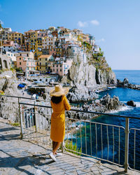 Rear view of woman standing by railing against sea