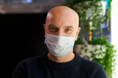 Close up portrait of a bald man with a protective mask on his face looks