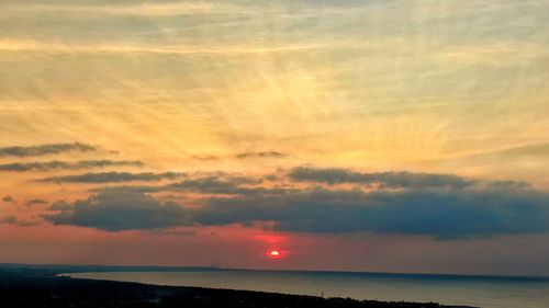 Scenic view of sea against dramatic sky during sunset
