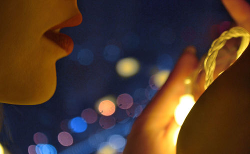 Close-up of woman against illuminated lighting equipment