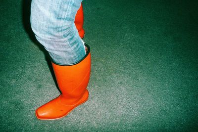 Low section of person in rubber boot standing on road