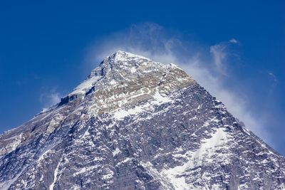 Low angle view of snowcapped mountain against blue sky