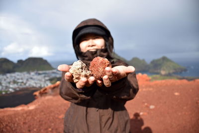 Smiling woman holding rocks while standing on mountain