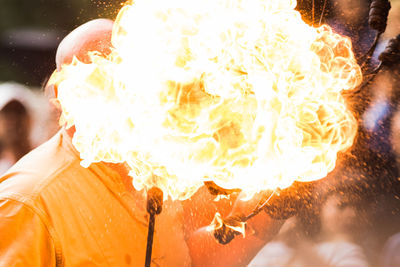 Close-up of man holding fire against blurred background