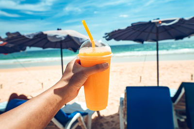 Cropped image of hand holding drink at swimming pool