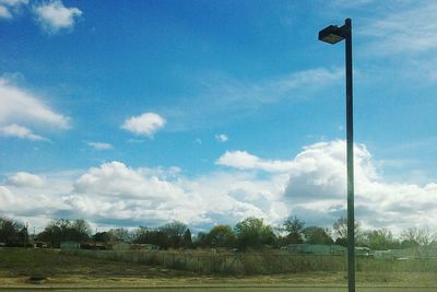 Trees on field against cloudy sky