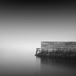 Pier by sea against sky during foggy weather