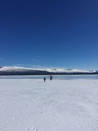 People on snowcapped mountain against blue sky