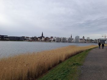 Scenic view of river by buildings against sky