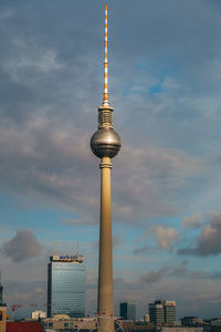 Communications tower in city against sky