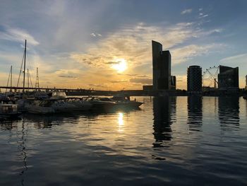 Sailboats in sea against sunset sky
