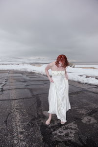 Full length of young woman standing on frozen shore