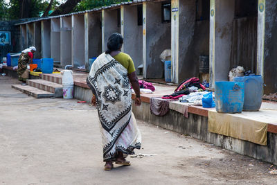 Rear view of woman with umbrella walking outdoors