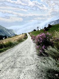 Scenic view of road amidst grassy field against sky