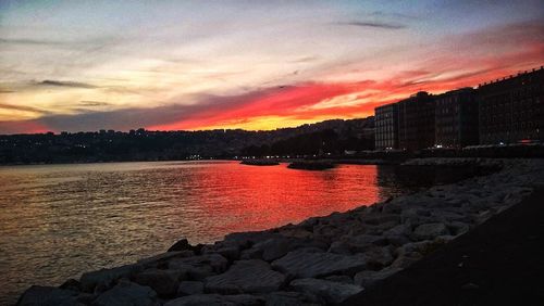 Sea by city against sky during sunset