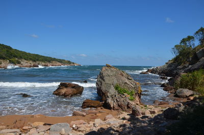 Scenic view of rocks on beach against blue sky