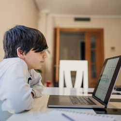 Serious school boy studying maths at home. home schooling and distance learning concept