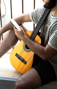 Midsection of man playing guitar