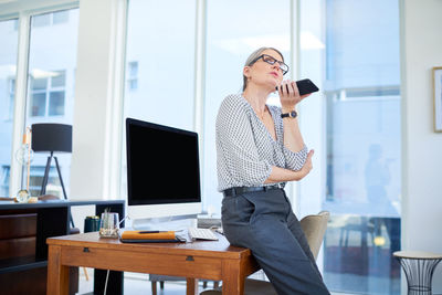 Side view of young woman using mobile phone in office