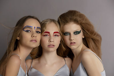 Portrait of girls standing against gray background