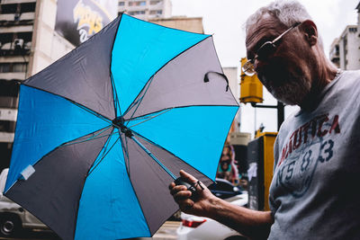 Midsection of woman holding umbrella on rainy day