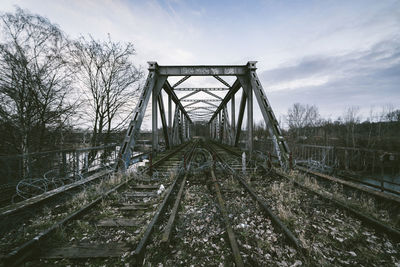 Barbed wire fence on abandoned railroad tracks against sky