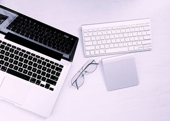 Directly above shot of laptop with keyboard and eyeglasses at desk