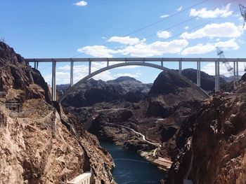 Bridge over river against cloudy sky