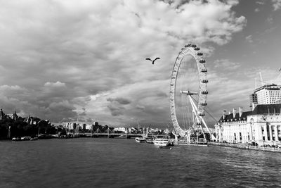 Ferris wheel in city against cloudy sky