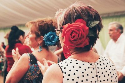 Midsection of women with red flowers