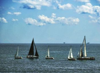 Sailboats sailing in sea against sky