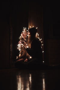 Side view of couple sitting in illuminated room