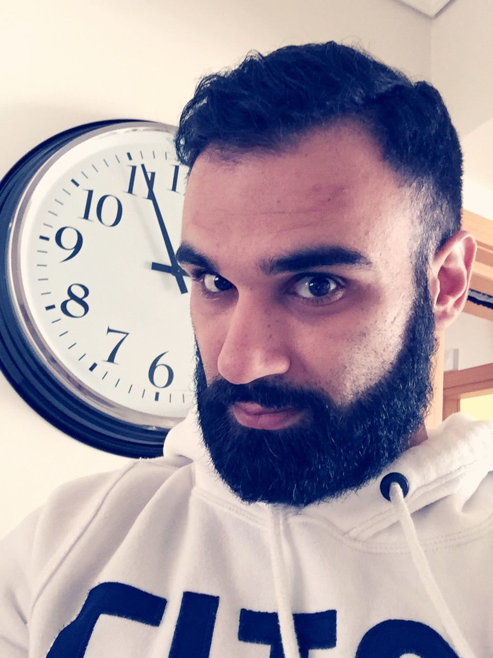 indoors, communication, young adult, front view, text, close-up, time, person, lifestyles, western script, clock, young men, leisure activity, beard, looking at camera, portrait, holding, headshot