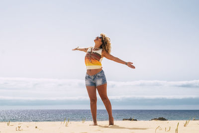 Full length of woman standing at beach against sky