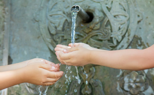 Midsection of woman holding water at faucet