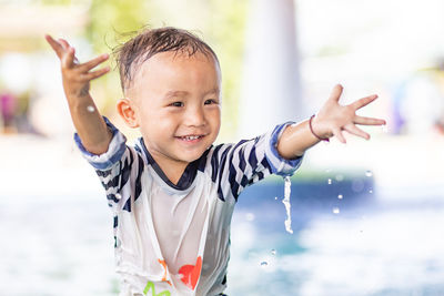 Cute boy with arms raised in swimming pool