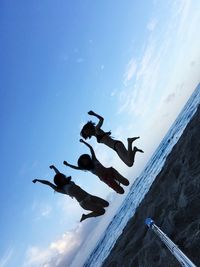 Tilt shift image of women jumping at waikiki beach against sky