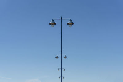 Low angle view of street lights against clear blue sky