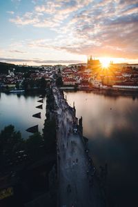 Scenic view of river by buildings against sky during sunset