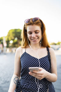 Happy woman listening to music and messaging on smartphone