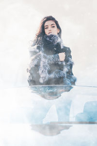 Portrait of woman standing in snow against sky