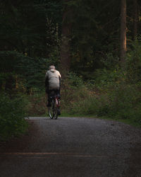 Rear view of man riding bicycle on road