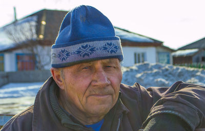 Close-up portrait of senior man in warm clothing standing against clear sky