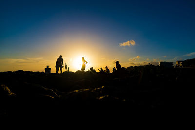 Silhouette of people on top of the beach rocks. late afternoon in salvador, bahia, brazil.