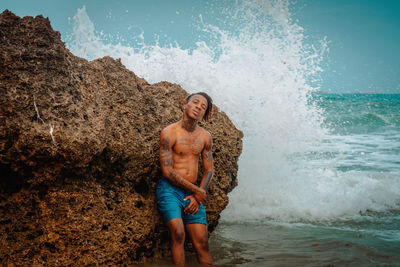 Full length of shirtless man at sea shore