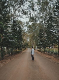 Man standing on road amidst trees