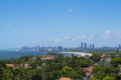 City at waterfront against blue sky