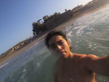 Beautiful young woman in sea against sky